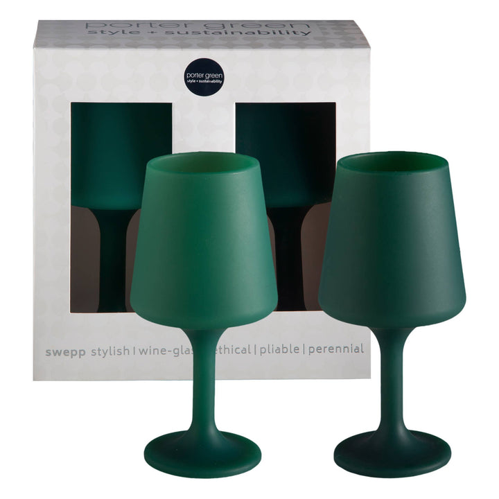 Two matte dark green silicone wine glasses in front of their white packaging box, which features a window showing the same green color.
