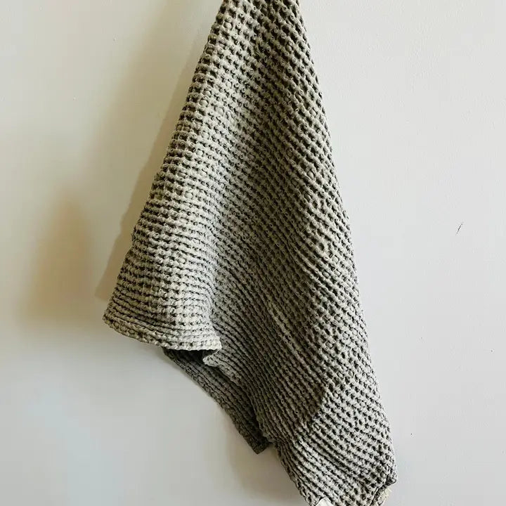 Textured khaki waffle tea towel draped over a white surface