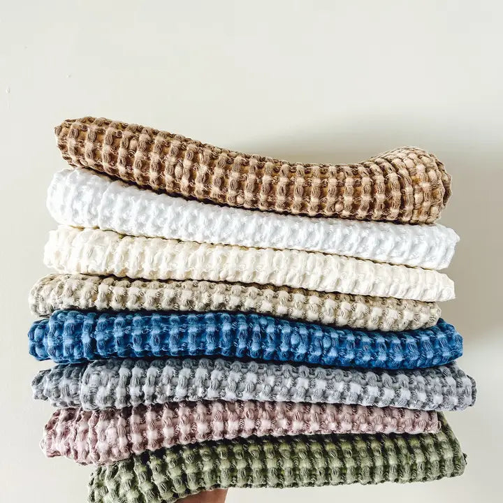 Stack of waffle-textured tea towels in various colors on a light background
