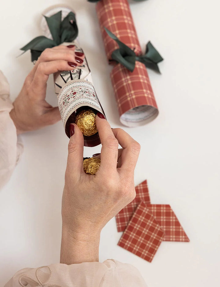 Person holding christmas cracker with plaid paper and gold chocolate candy