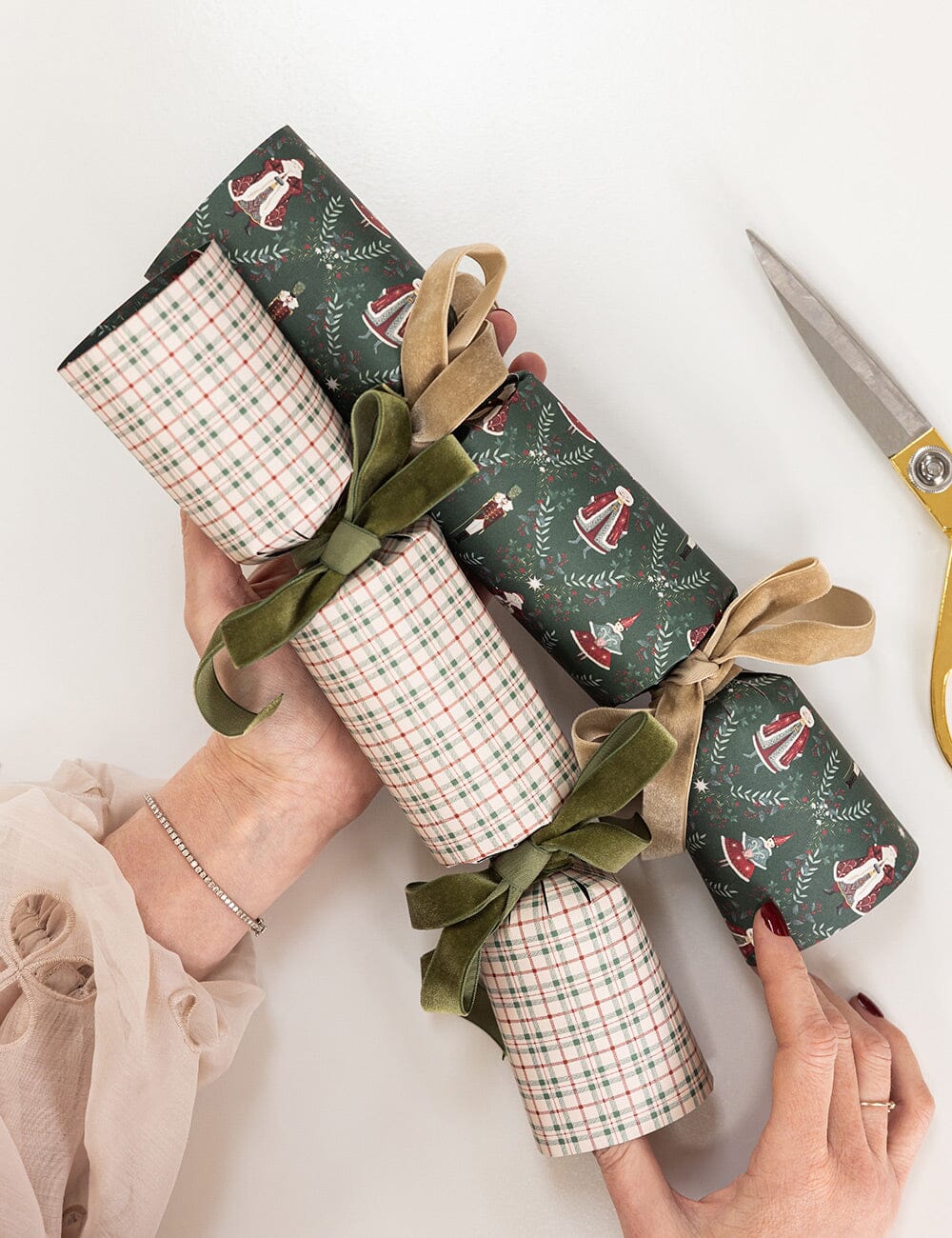 Three wrapped Christmas crackers with festive patterns and ribbons on a white background.