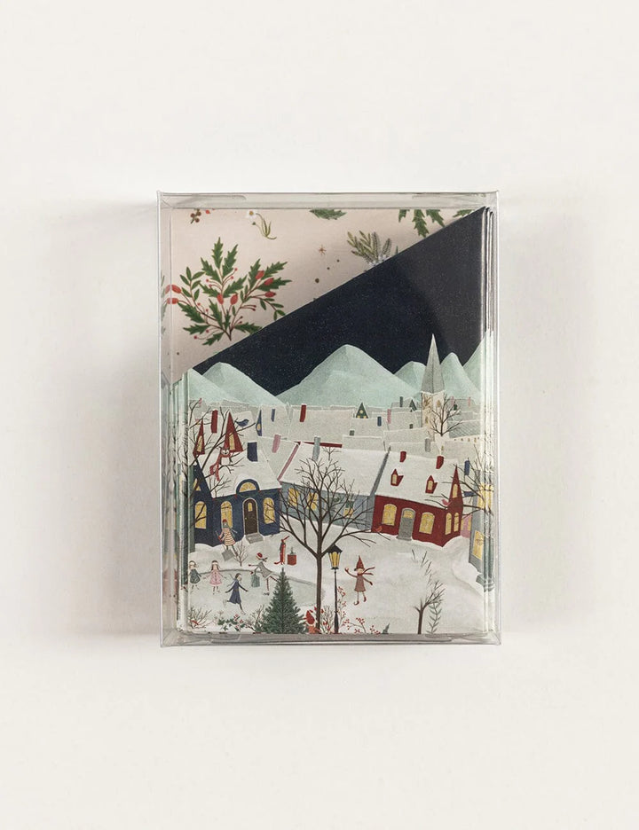 Paper crowns of a winter village scene with trees and buildings.