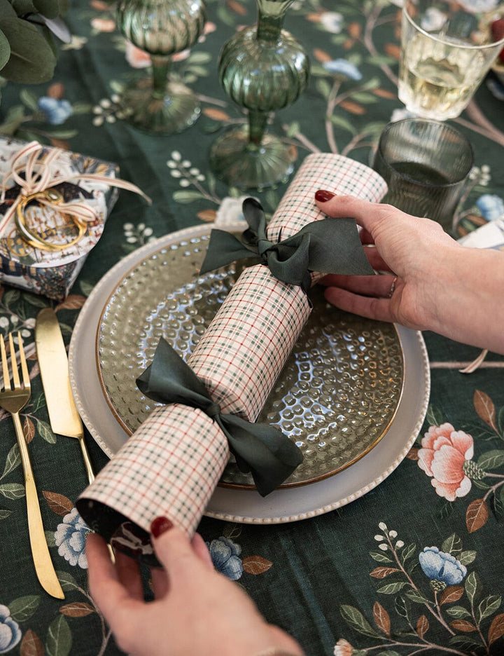Decorative cracker with a black bow on a table setting with floral tablecloth