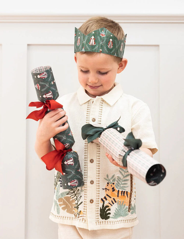 Child holding Christmas cracker and stocking with festive design against a white background