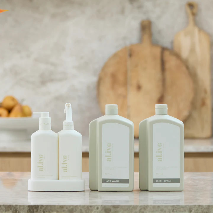 Set of cleaning products on a kitchen counter with wooden cutting boards in the background.