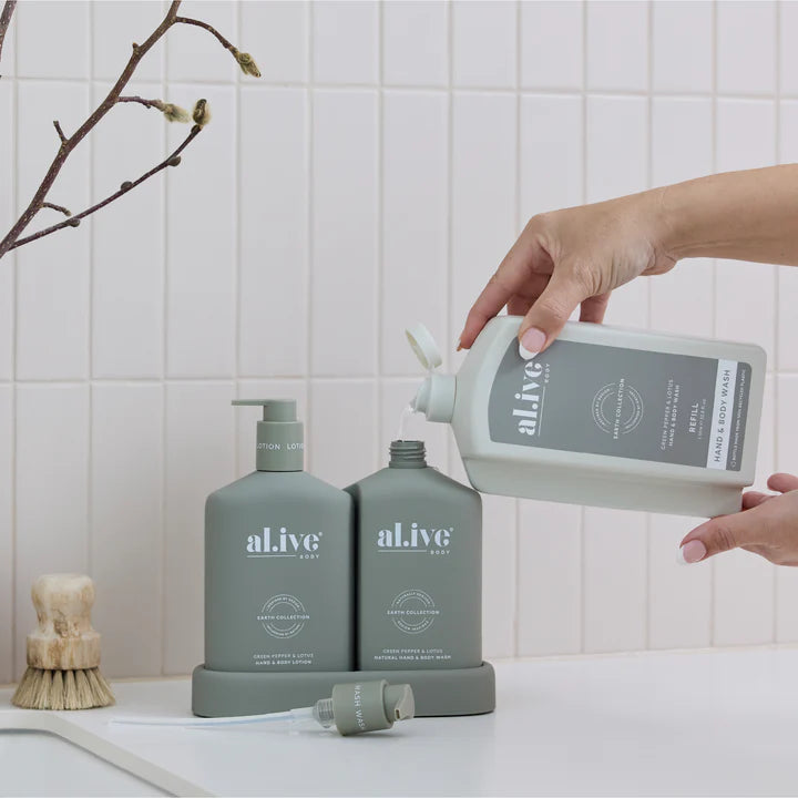 Person pouring liquid from a 'alive' bottle into another on a bathroom counter.