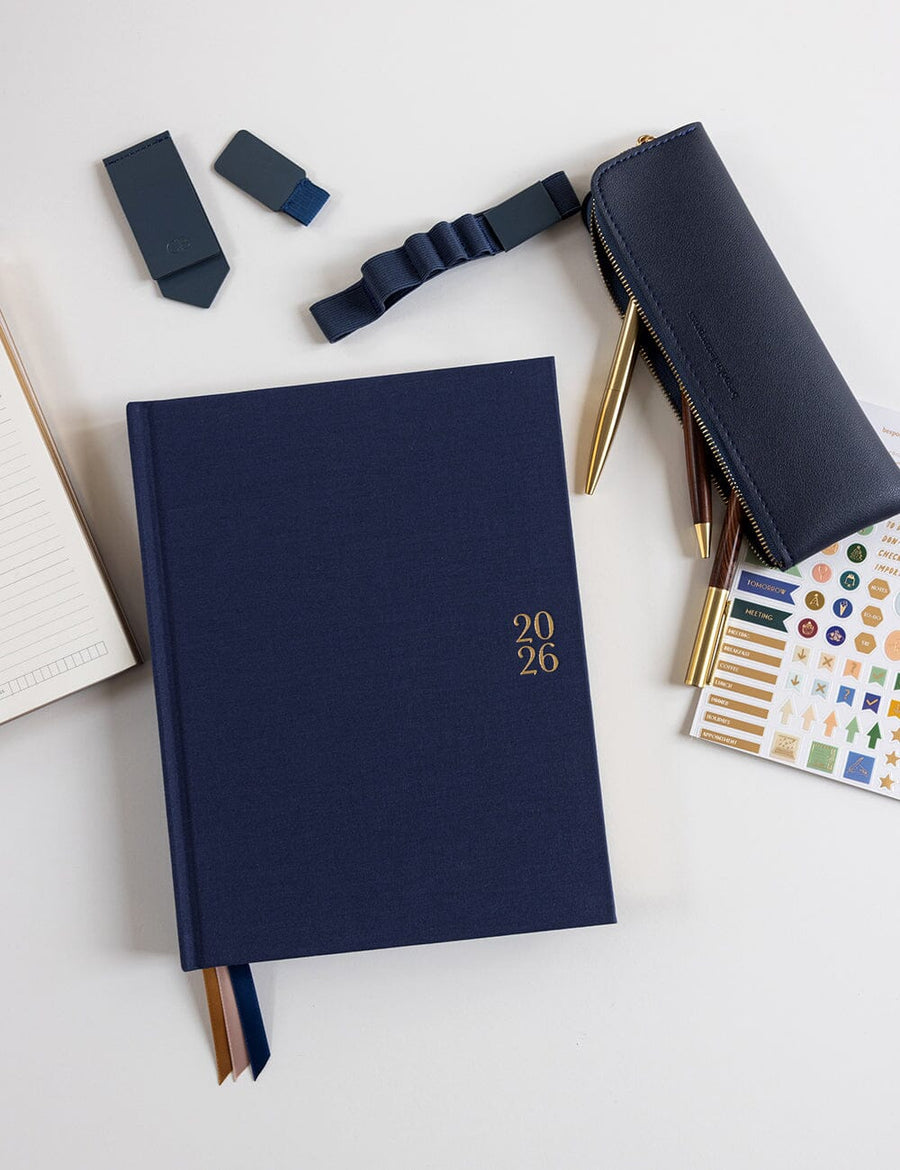 Navy blue planner with '2026' on a white surface with stationery items.