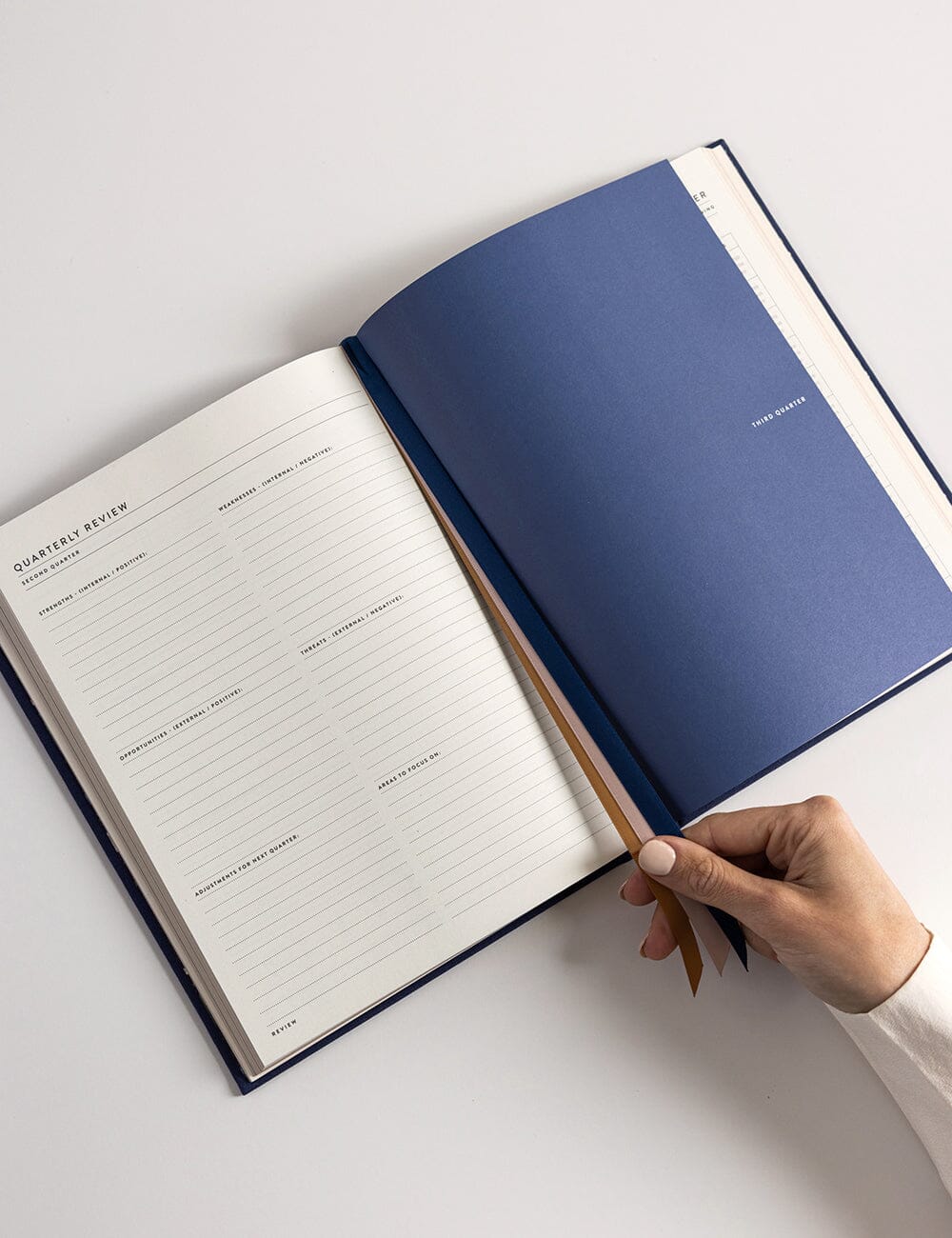 Open notebook with a hand holding it on a light gray background