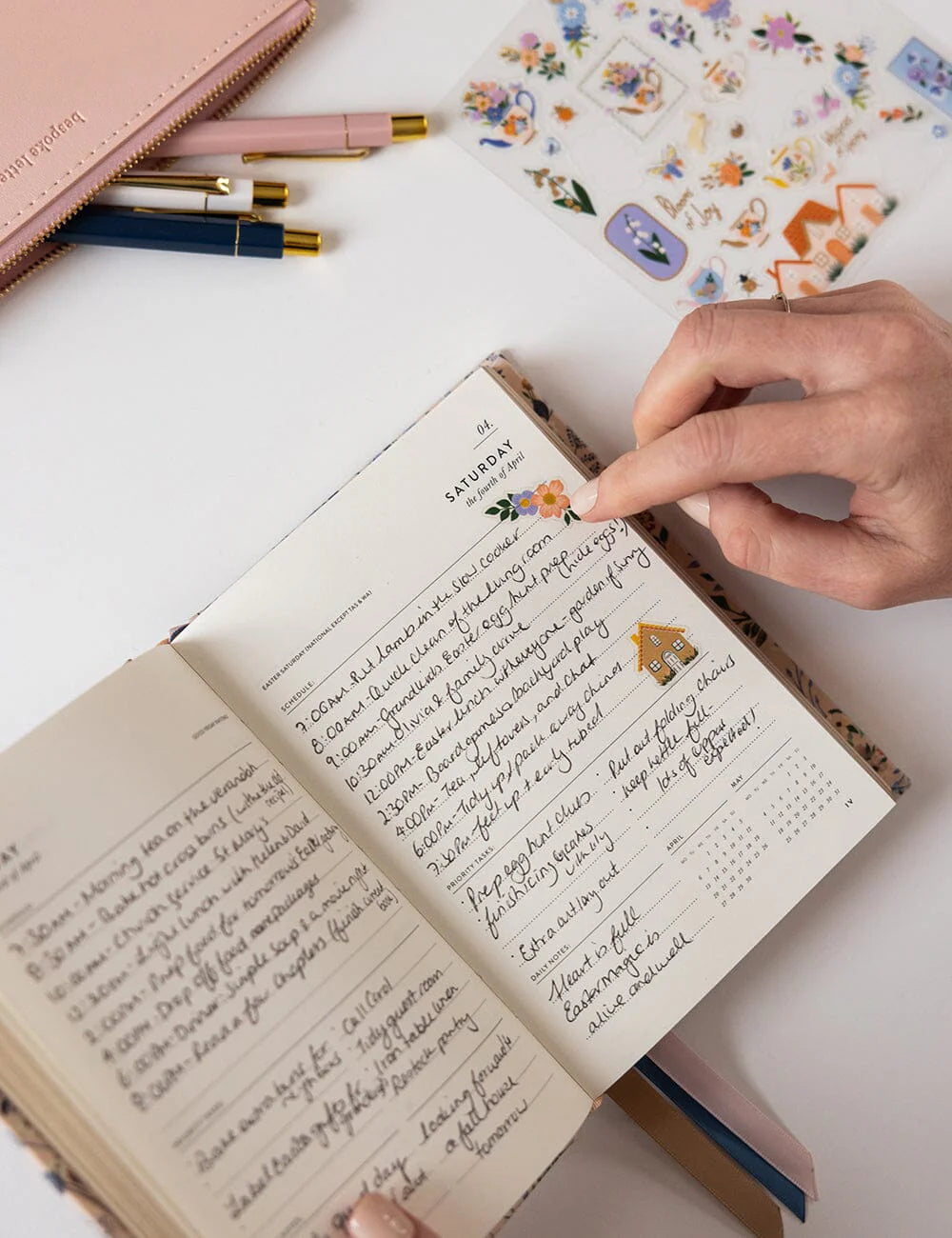 Handwritten journal entry in a notebook with stationery items on a white surface
