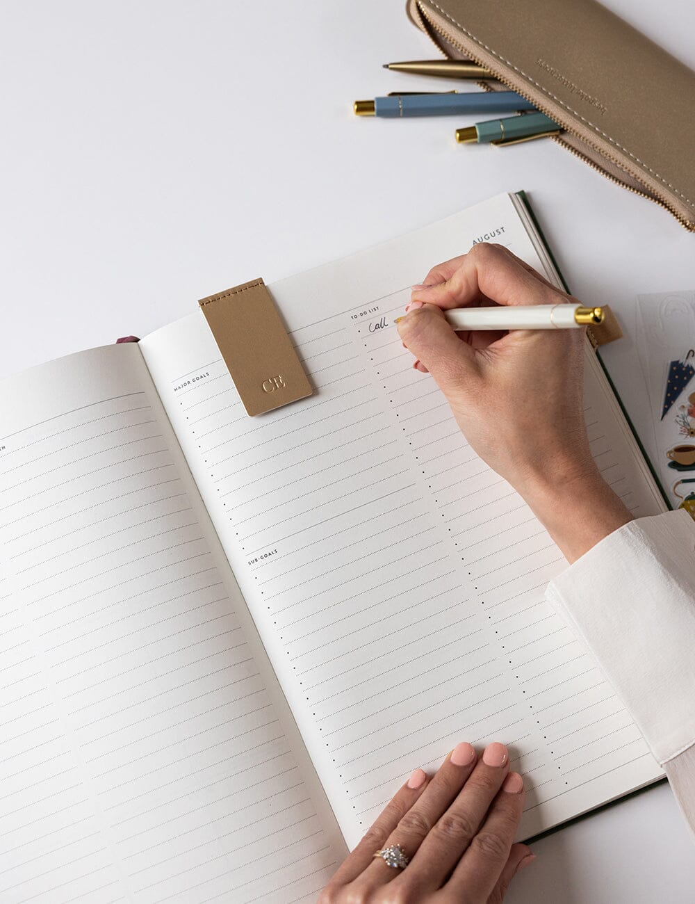 Hand writing in a notebook with a pen on a white surface