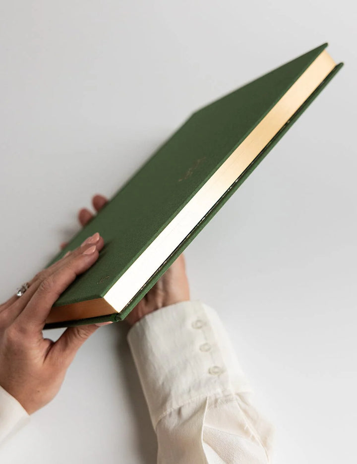 Person holding a green book on a light gray background