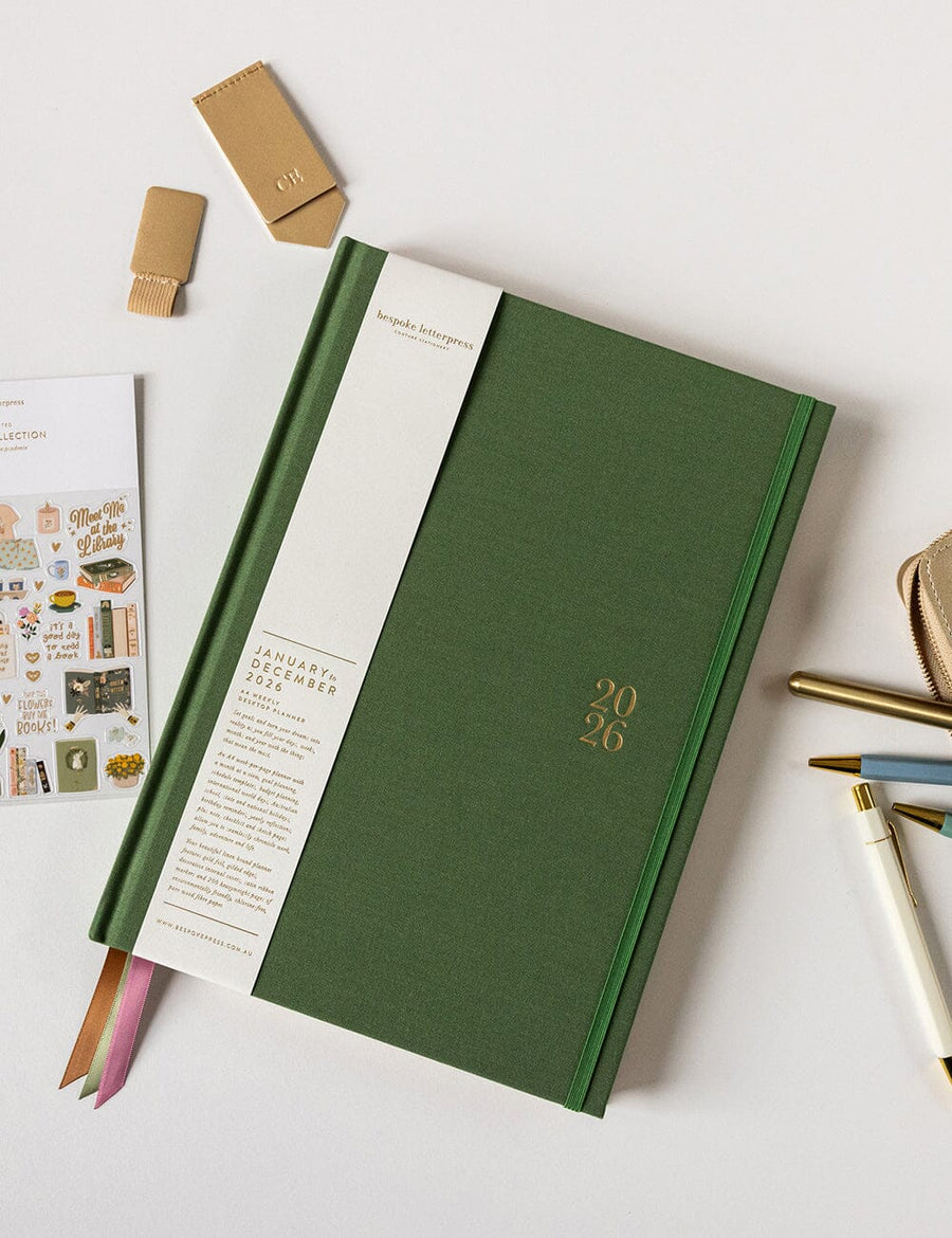 Green planner with 2026 on a white surface with stationery items.