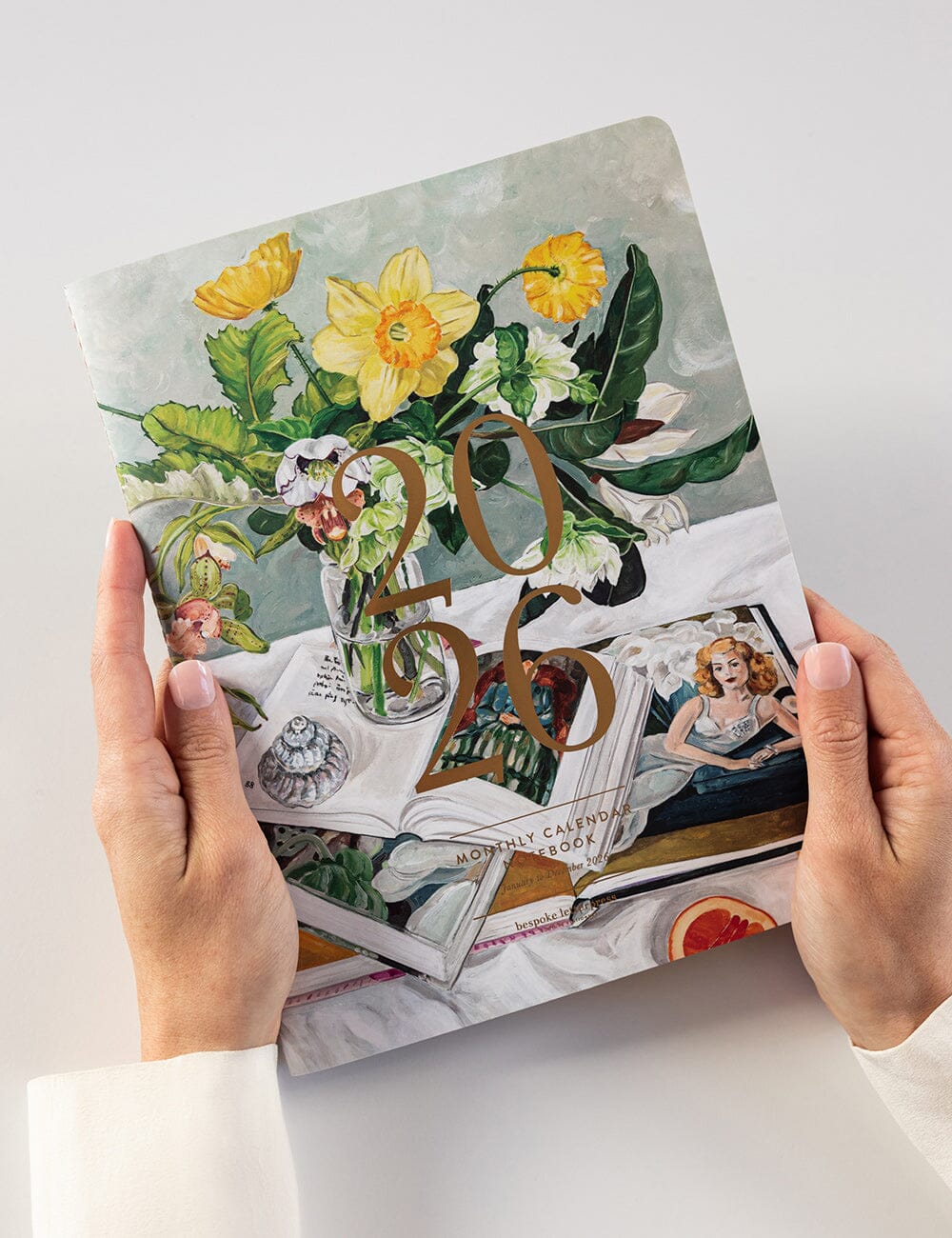 Floral-themed planner with vintage design held by hands on a light background
