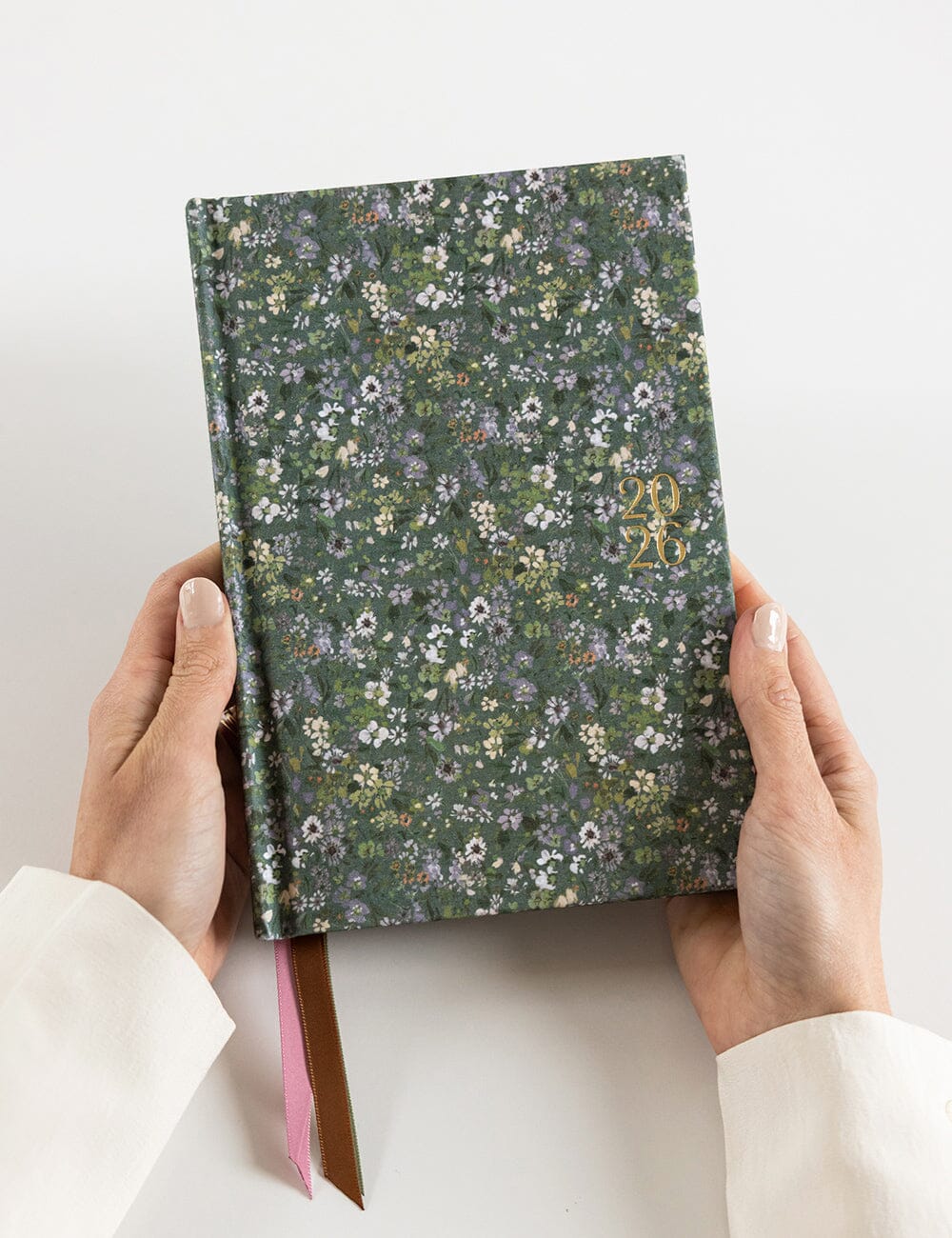 Floral-patterned notebook held by hands on a white background