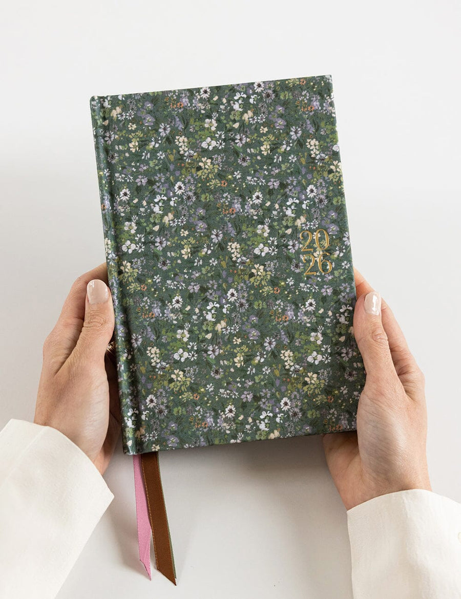 Floral-patterned notebook held by hands on a white background