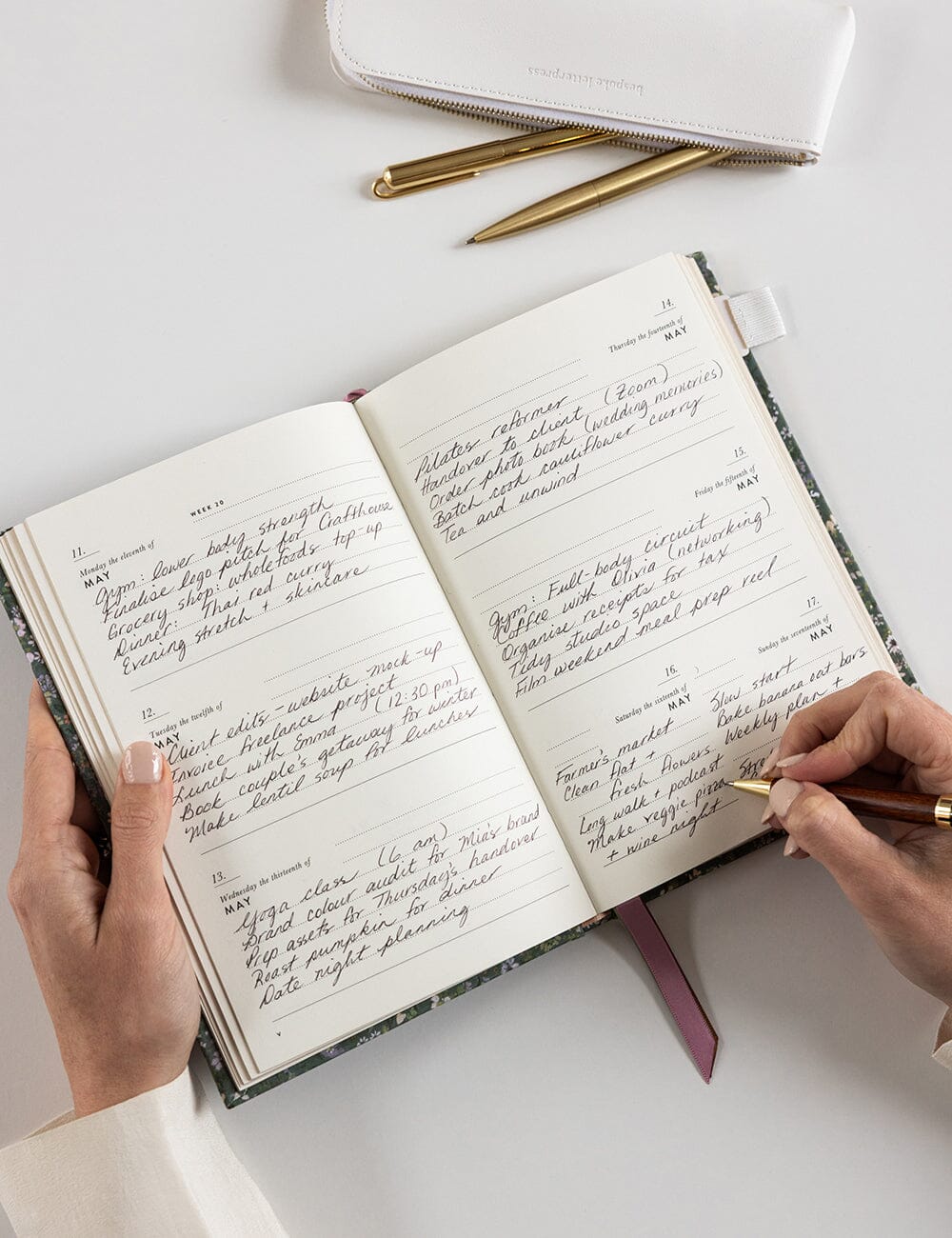 Person writing in a notebook with a pen on a white surface