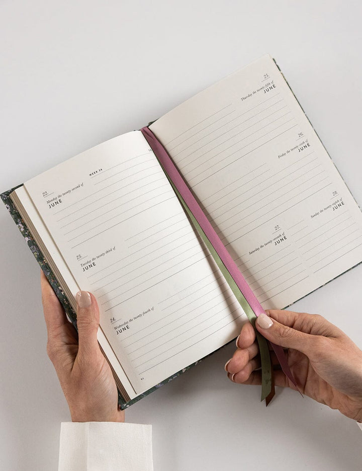 Open notebook held by hands on a light gray background