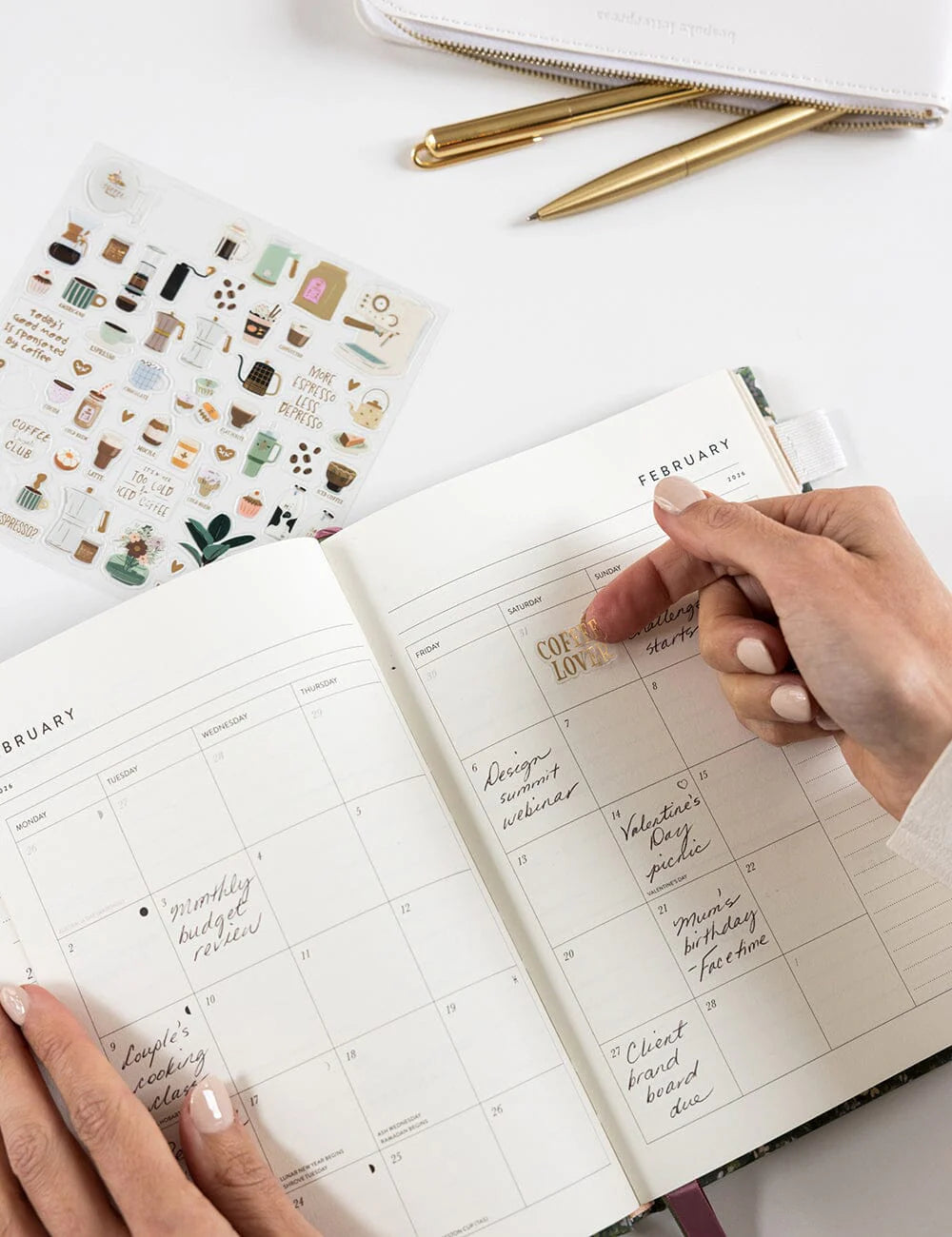 Person using a planner with stickers on a white surface
