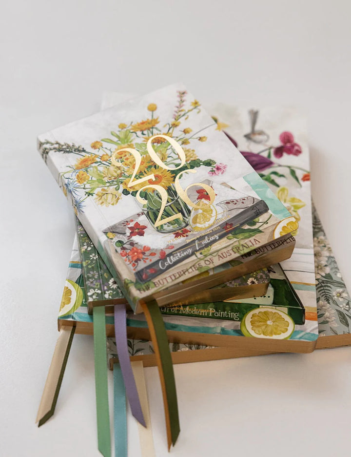 Stack of planners with colorful designs and text on a white background