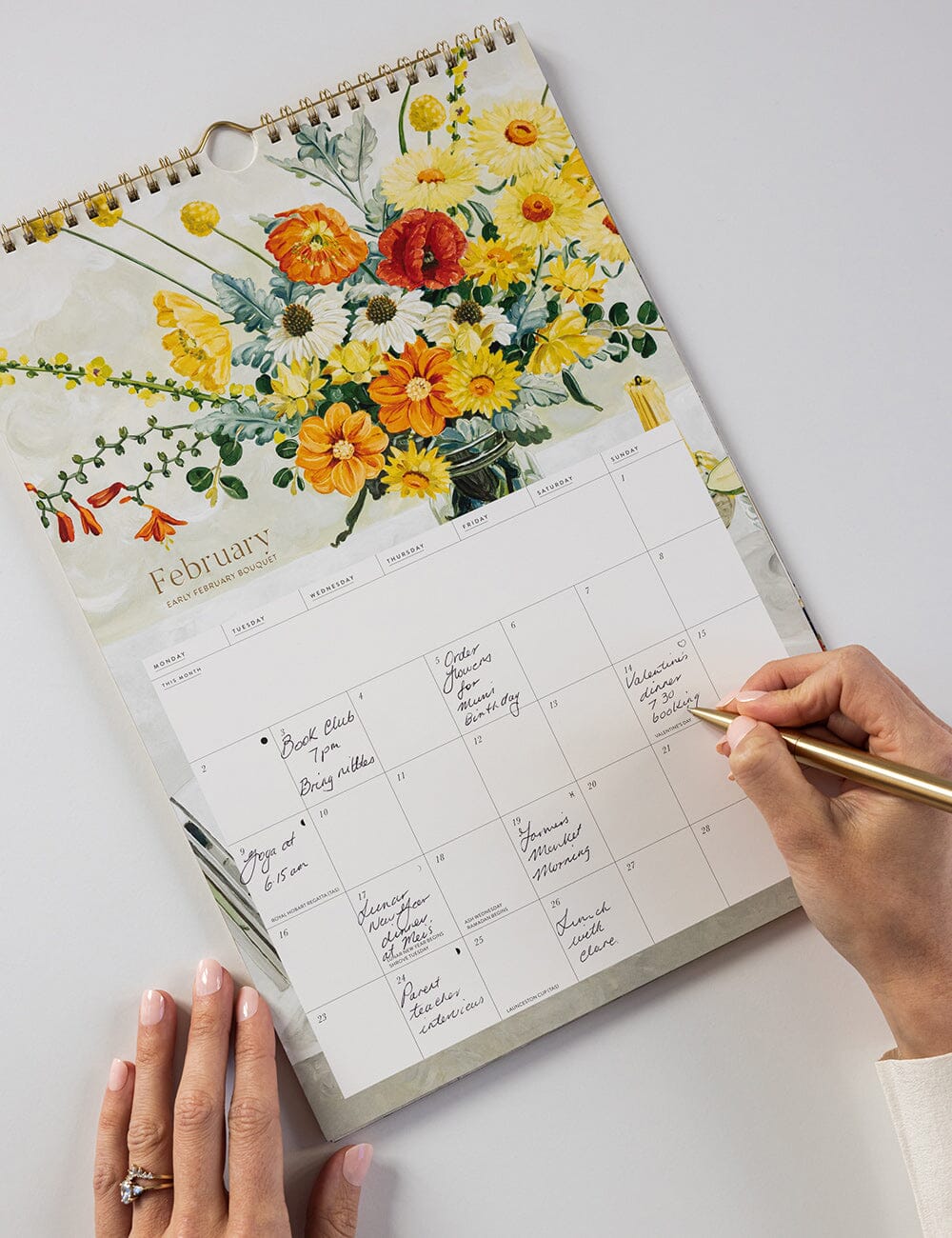Floral-themed calendar with a hand writing in it on a white surface