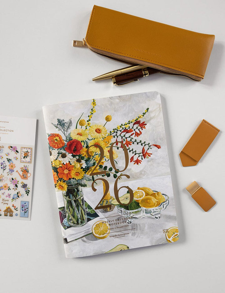 Floral-themed planner with a pen, envelope, and card on a light gray background
