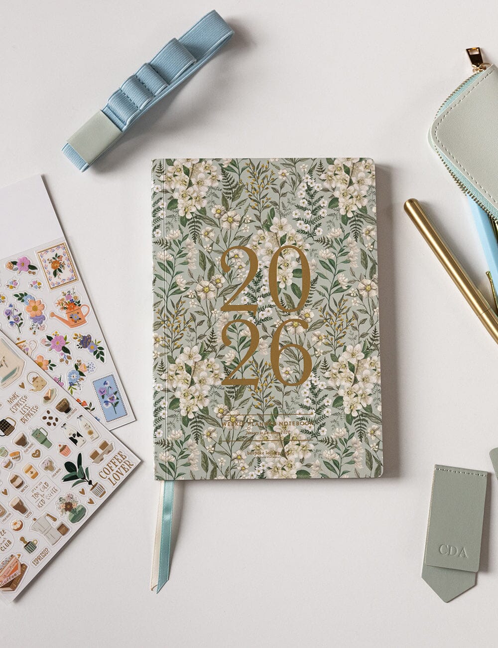 Floral notebook with '2026' design on a light surface with stationery items.