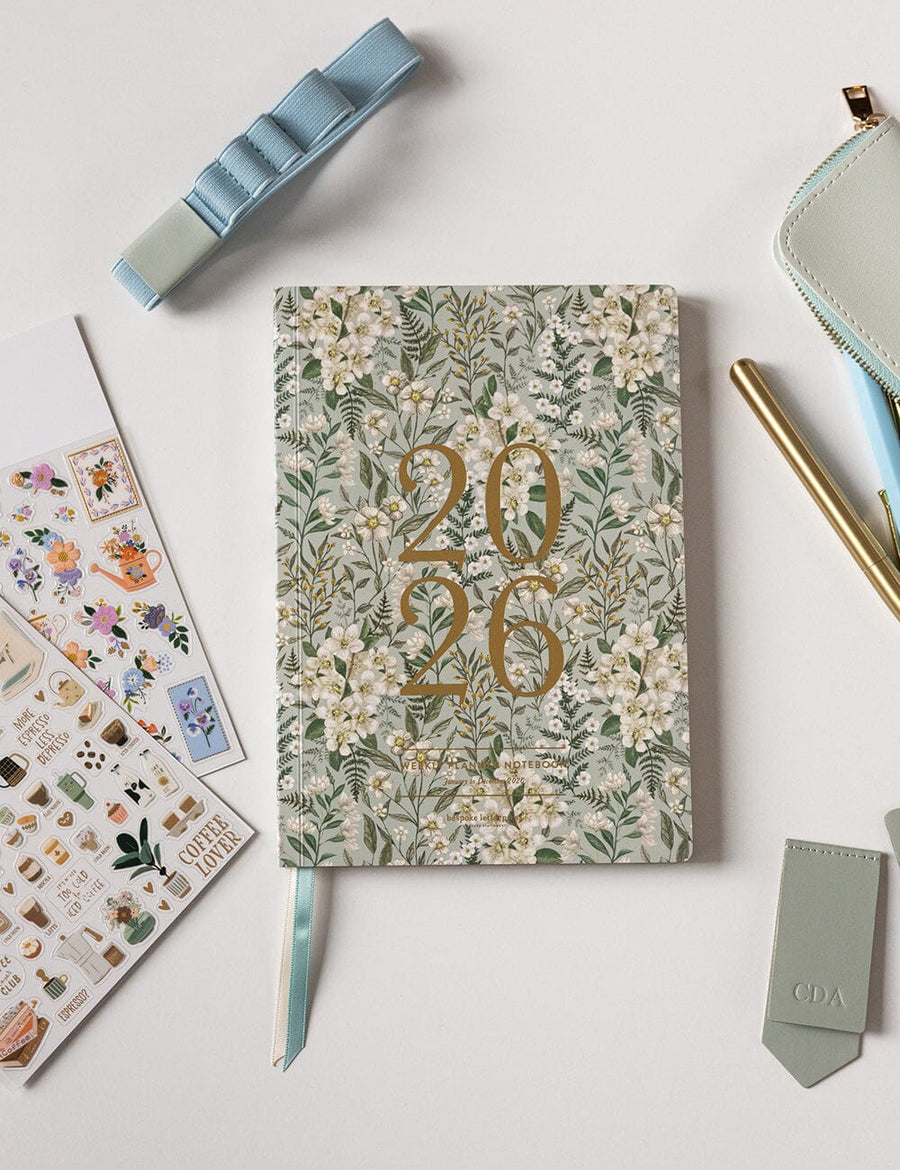 Floral notebook with '2026' design on a light surface with stationery items.
