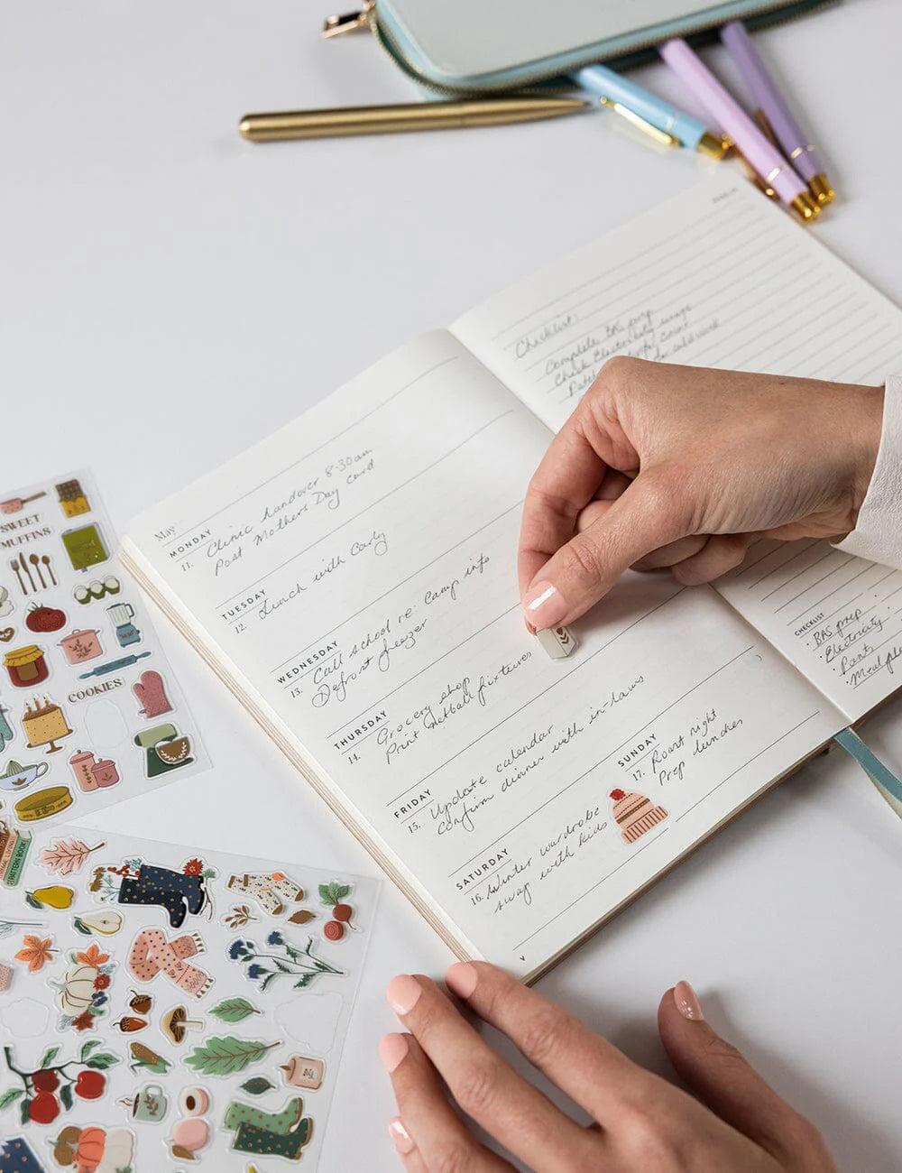 Handwritten notes in a notebook with decorative stickers and pens on a light surface