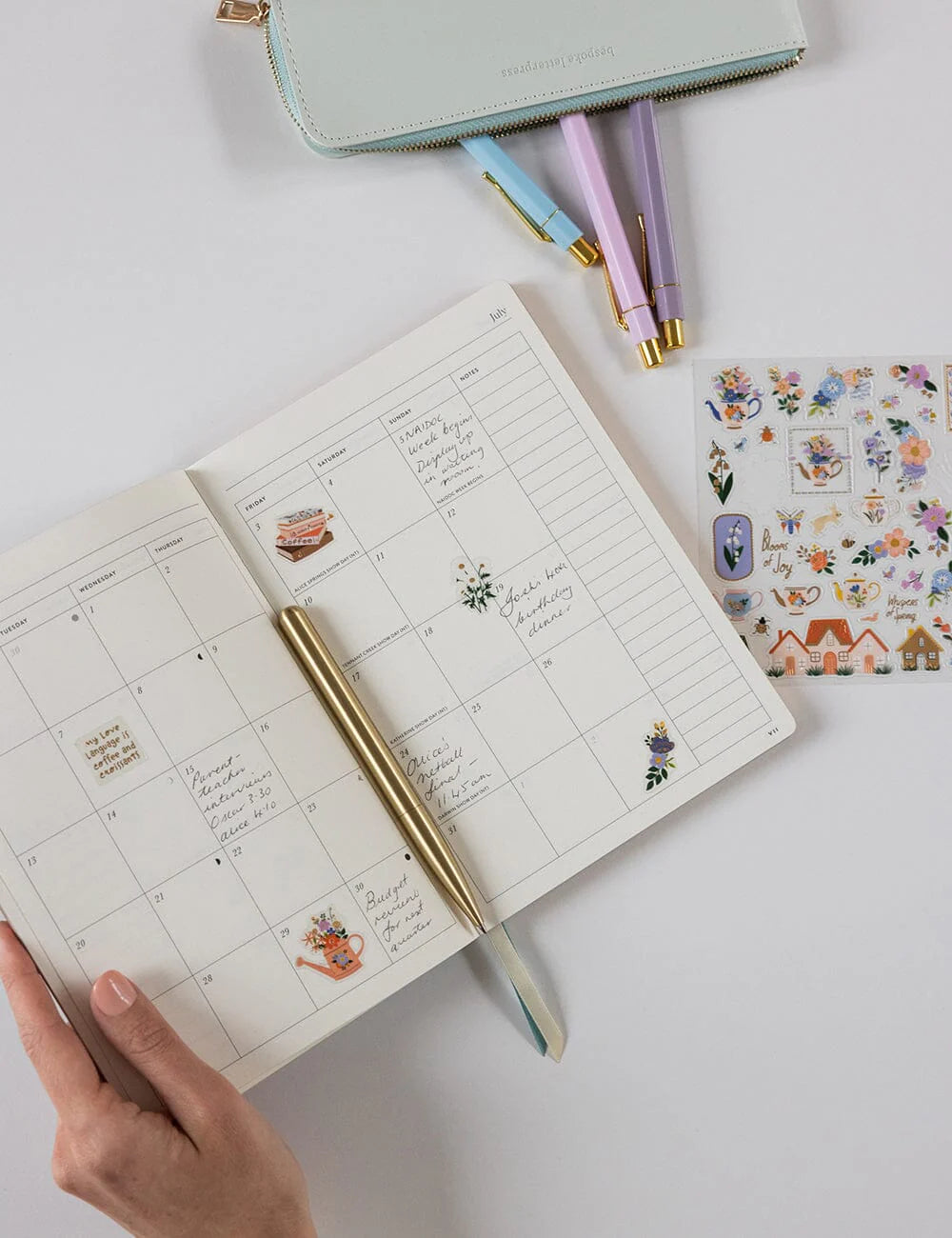 Open planner with stickers and pens on a white surface