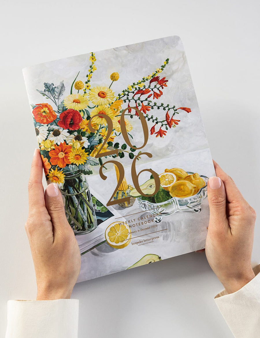 Product packaging with floral design and text held by hands on a light background