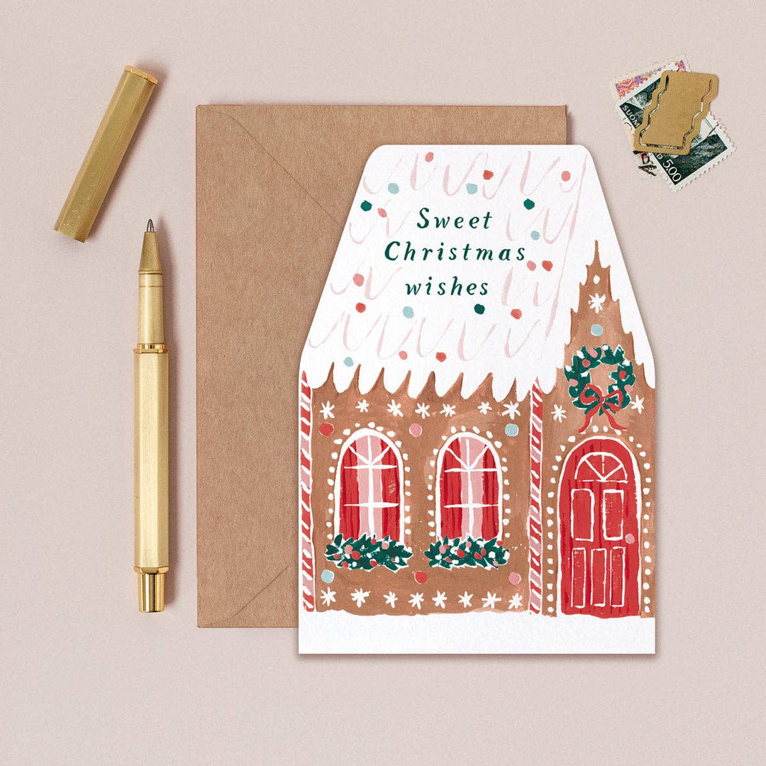 Greeting card with gingerbread house design and envelope on a beige background