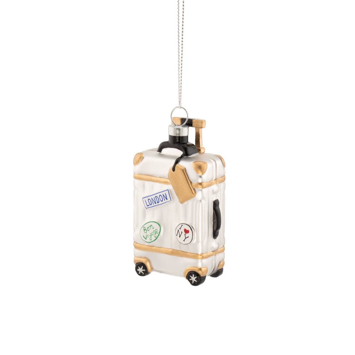 A white and gold miniature suitcase Christmas ornament with travel stickers, hanging from a silver string on a white background.