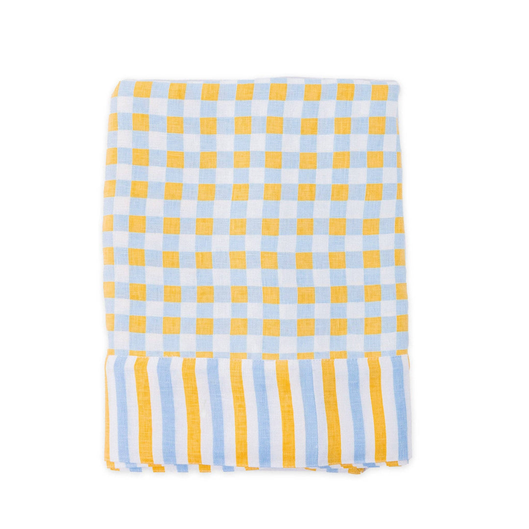 Yellow and chambray blue check patterned linen tablecloth laid flat on a white background