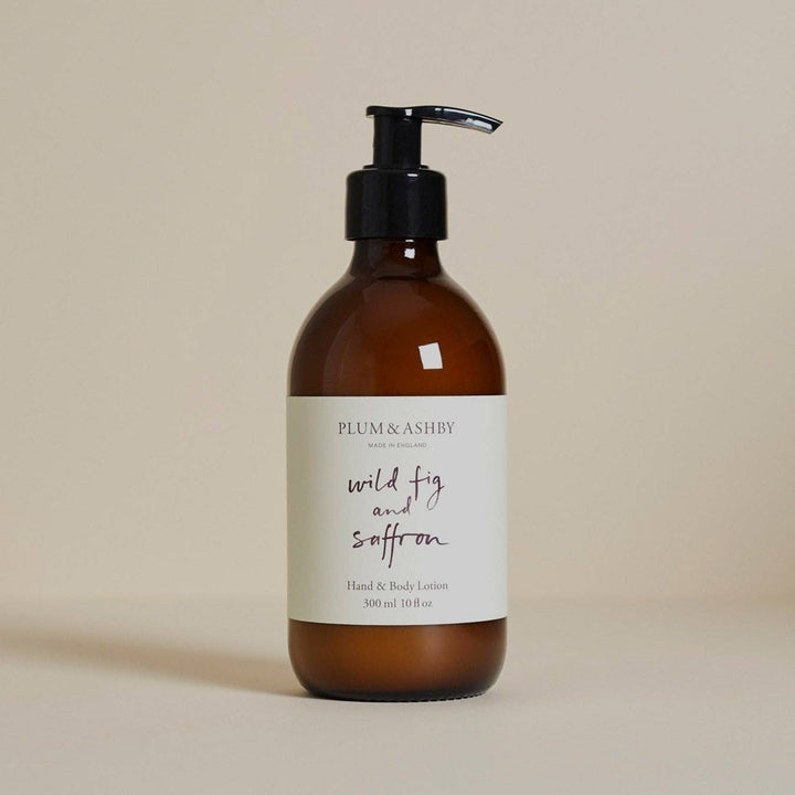 An amber glass pump bottle of Plum &amp; Ashby Hand &amp; Body Lotion with a black pump and a cream label reading &
