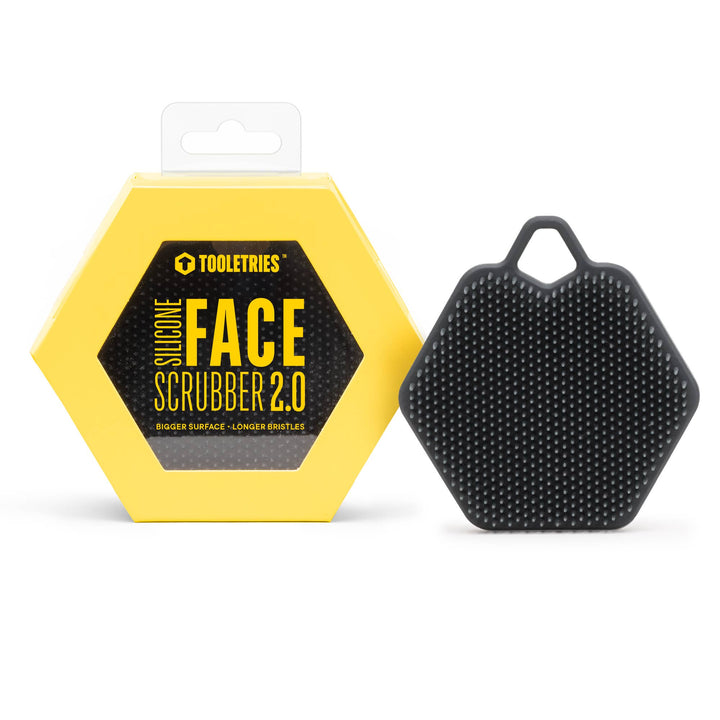 Black silicone face scrubber with packaging on a white background