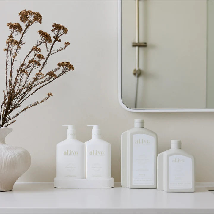 White ceramic bottles with 'alive' branding on a shelf against a neutral wall.