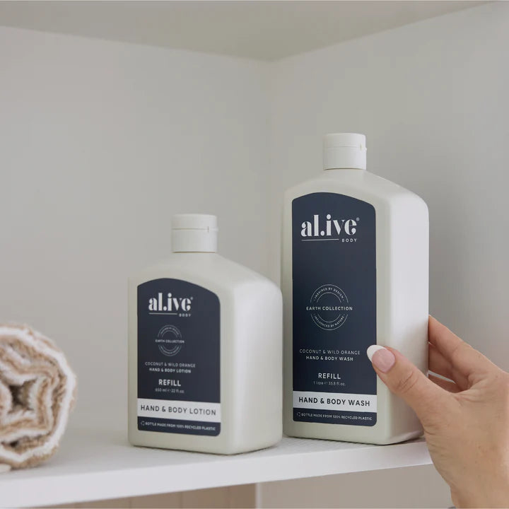 Hand holding a bottle of 'alive' hand and body wash on a shelf with another bottle in the background.