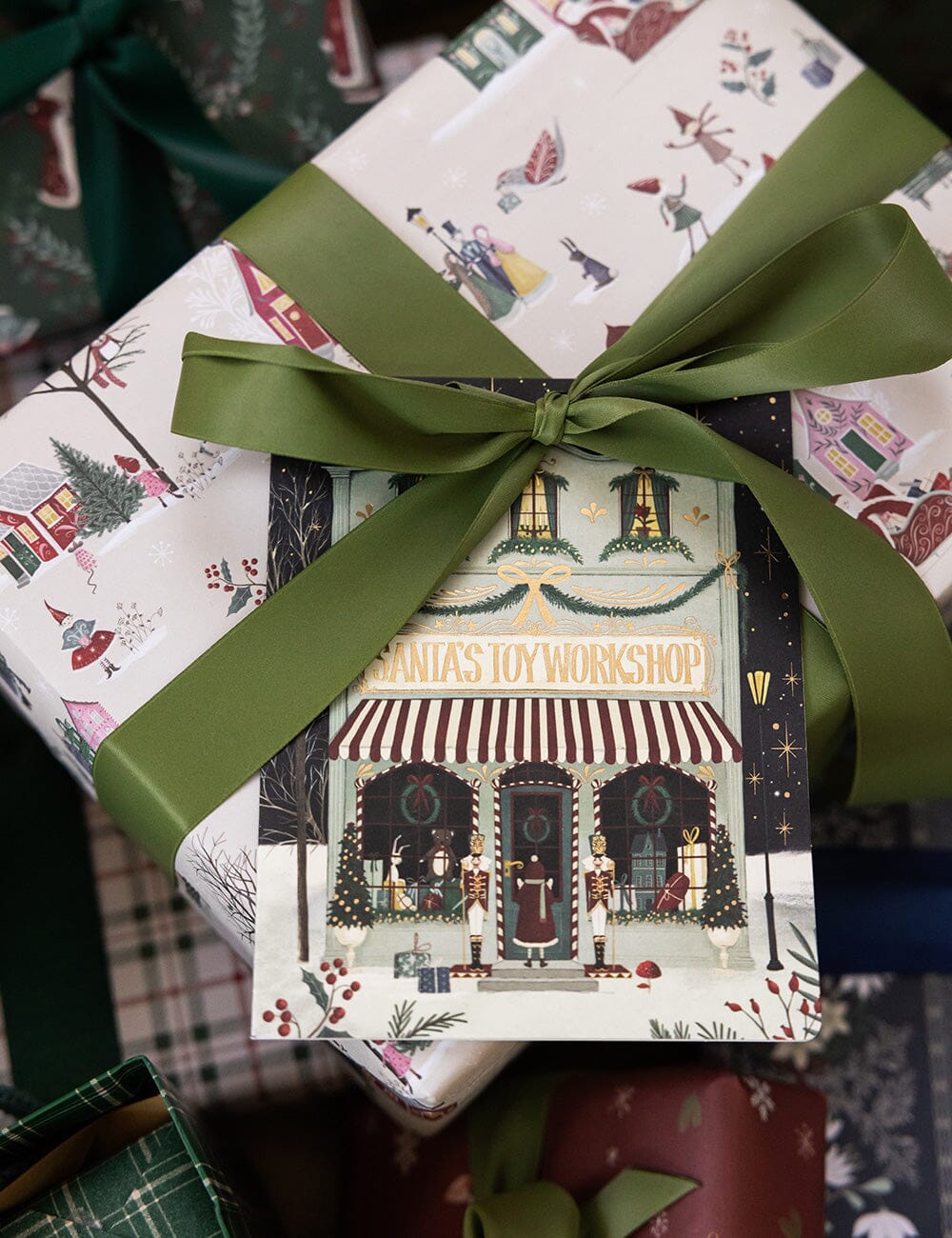 Gift box with festive design and green ribbon on a patterned surface