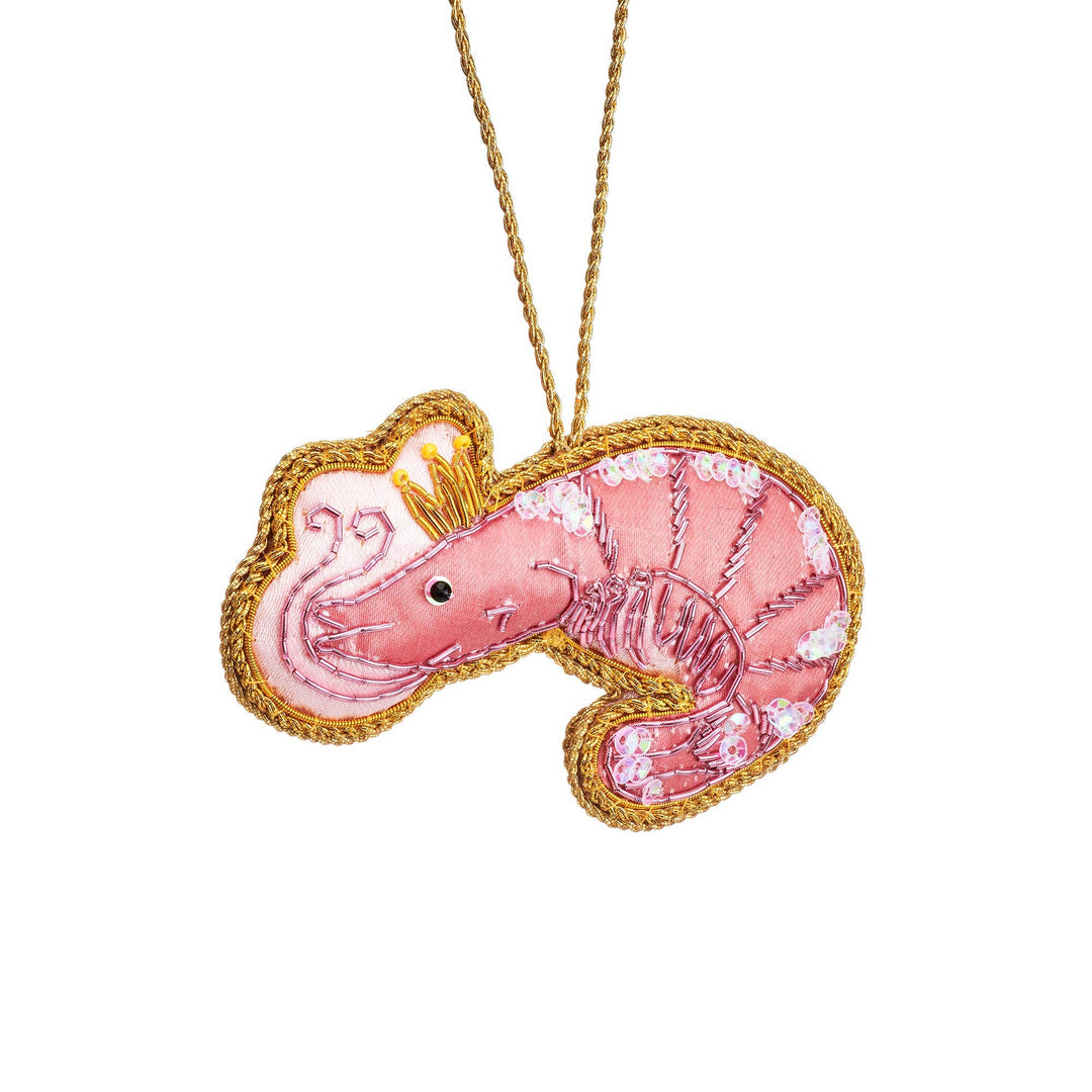 A pink embroidered prawn-shaped Christmas decoration with a gold braided border and a gold hanging cord, shown on a plain white background.