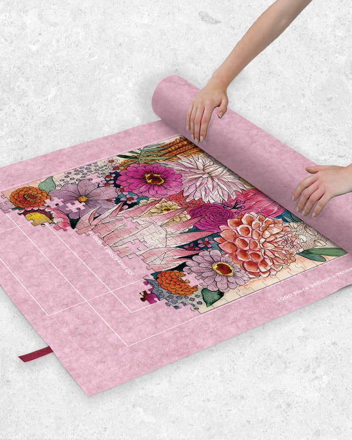 Person unrolling a floral puzzle on a pink puzzle mat