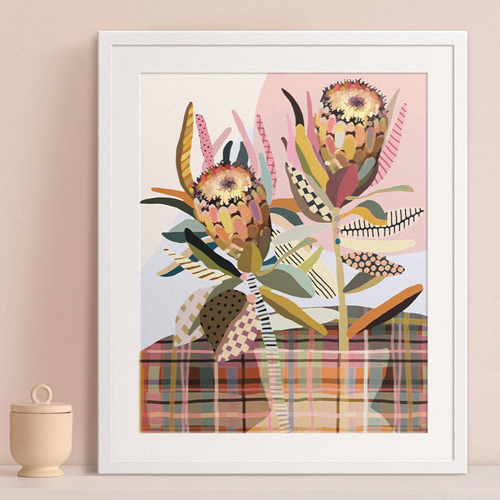 Framed artwork with a colorful floral design on a beige wall.