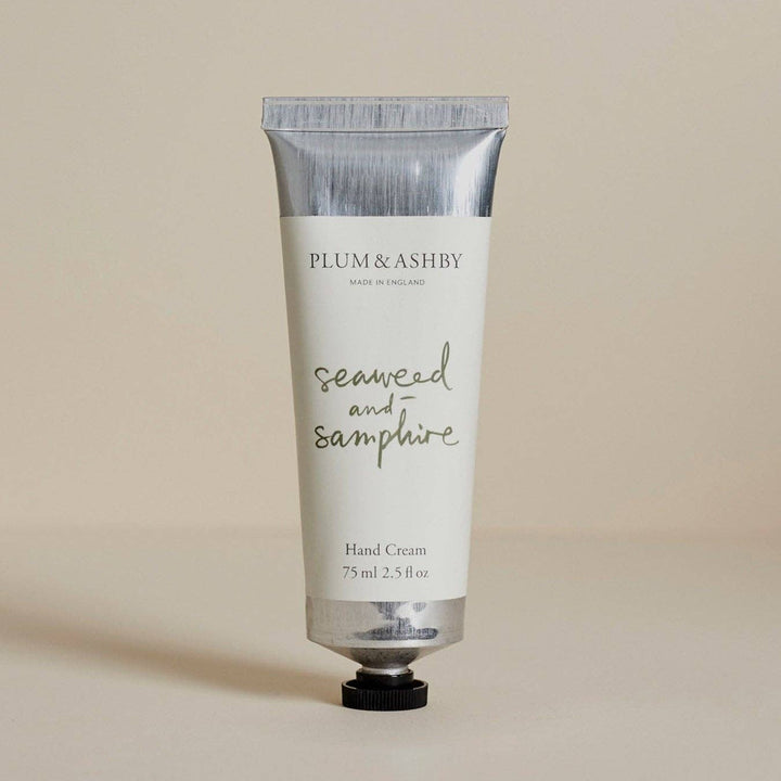 A squeeze tube of Plum &amp; Ashby Seaweed and Samphire Hand Cream, featuring a white body with silver metallic accents and a black cap, set against a solid beige background.