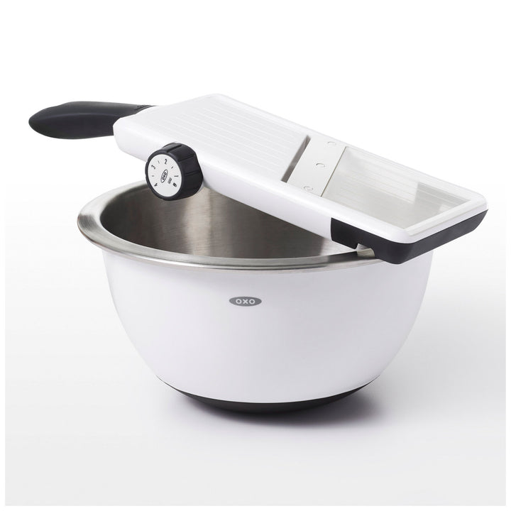 White mandoline slicer with stainless steel bowl on a white background