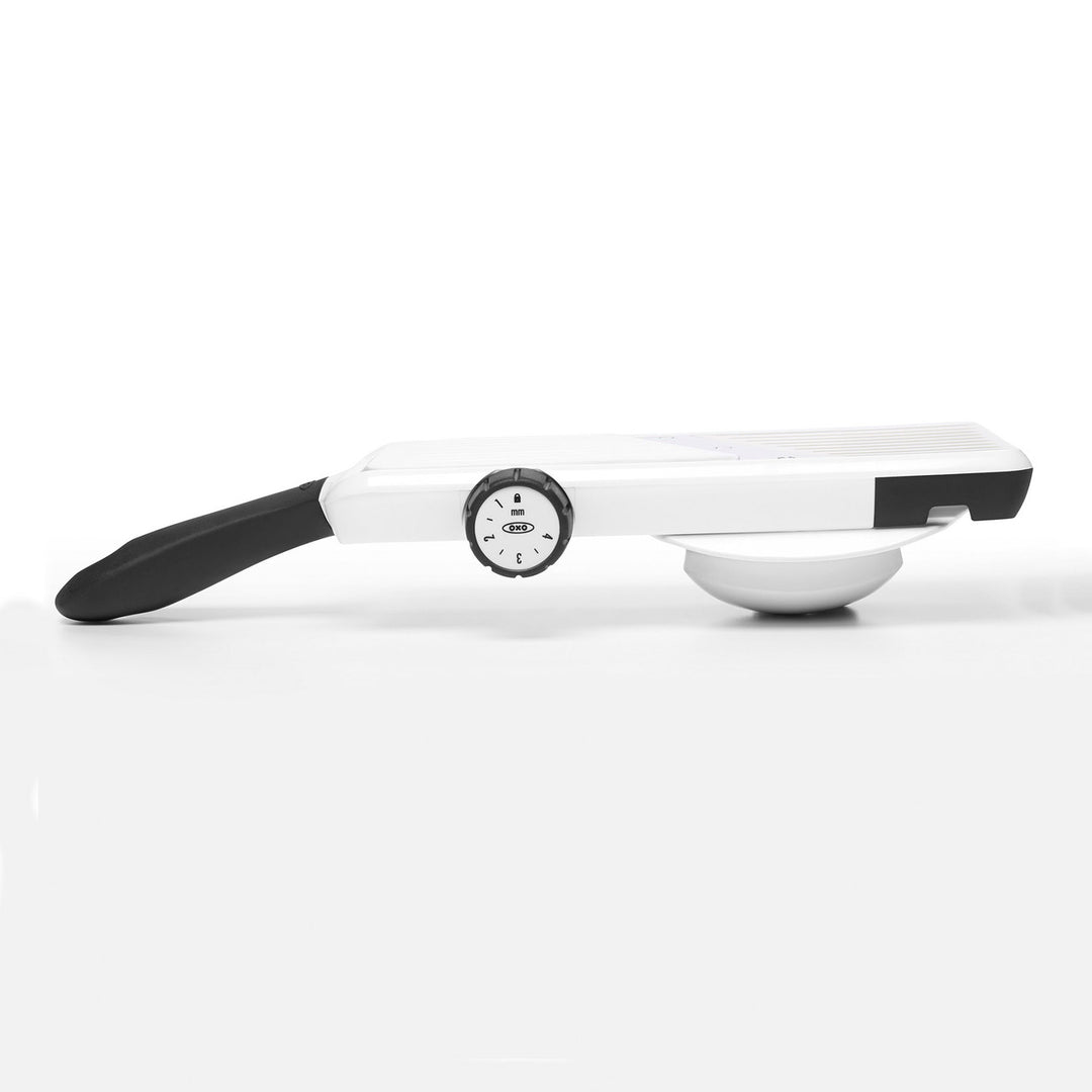 White mandoline slicer with black handle on a white background