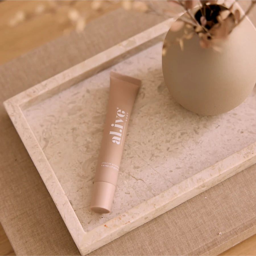 Tube of skincare product on a textured surface with a vase in the background