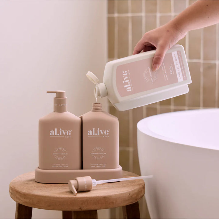 Person pouring a product from a bottle labeled 'alive' into a container on a wooden stool with more 'alive' products in the background.