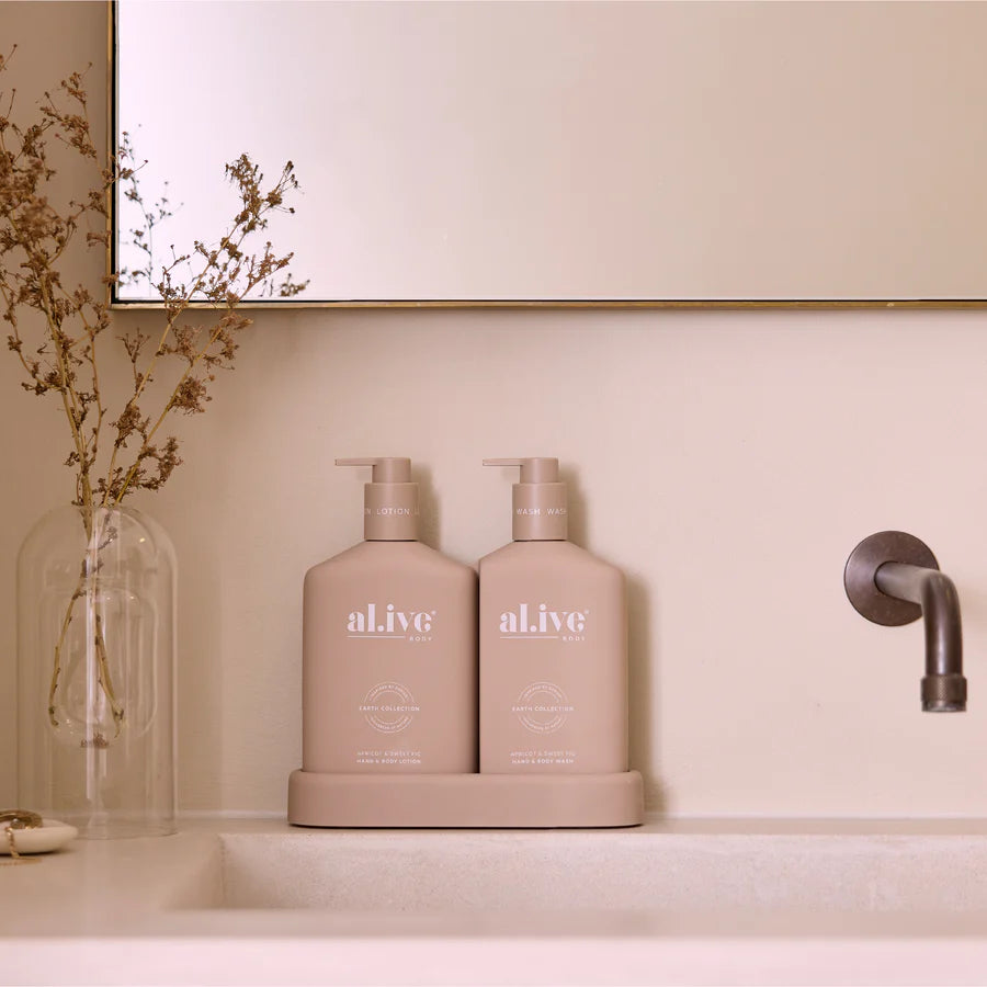 Two 'alive' bottles on a bathroom counter with a mirror and decorative elements in the background.
