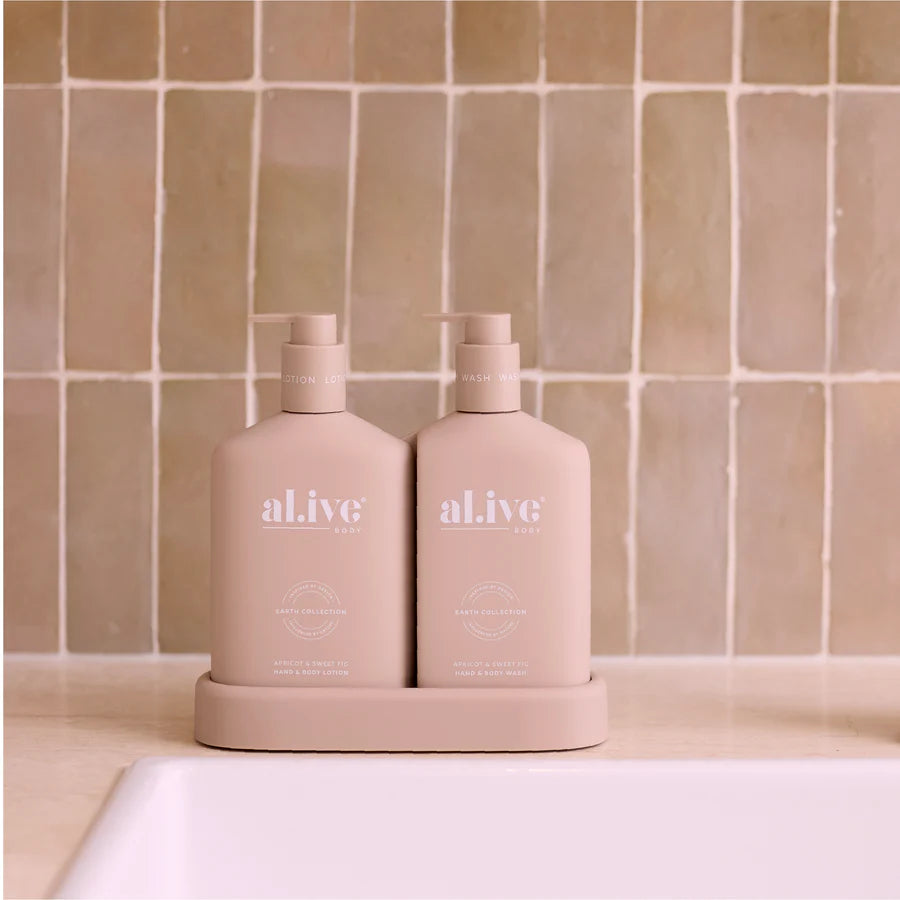 Two pink bottles labeled 'al.ive' on a beige tiled bathroom wall background.