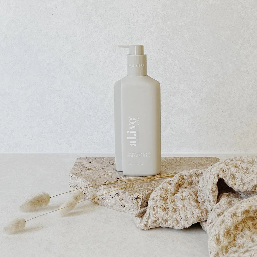 White bottle labeled 'alive' on a textured surface with a light background
