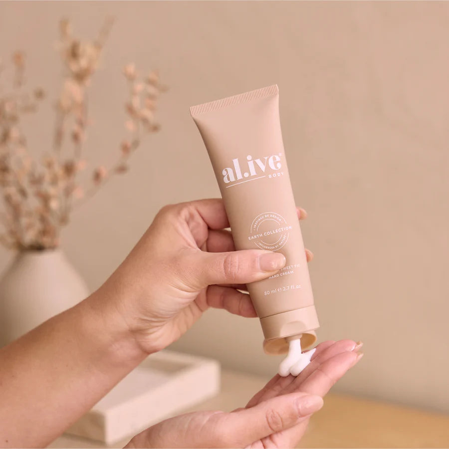 Hand holding a tube of 'al ive' cream with a blurred indoor background